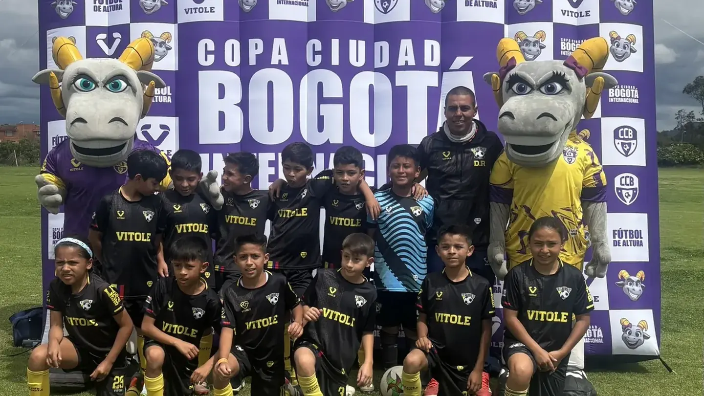 Equipo infantil frente al backdrop oficial de la Copa Ciudad Bogotá con las mascotas del torneo