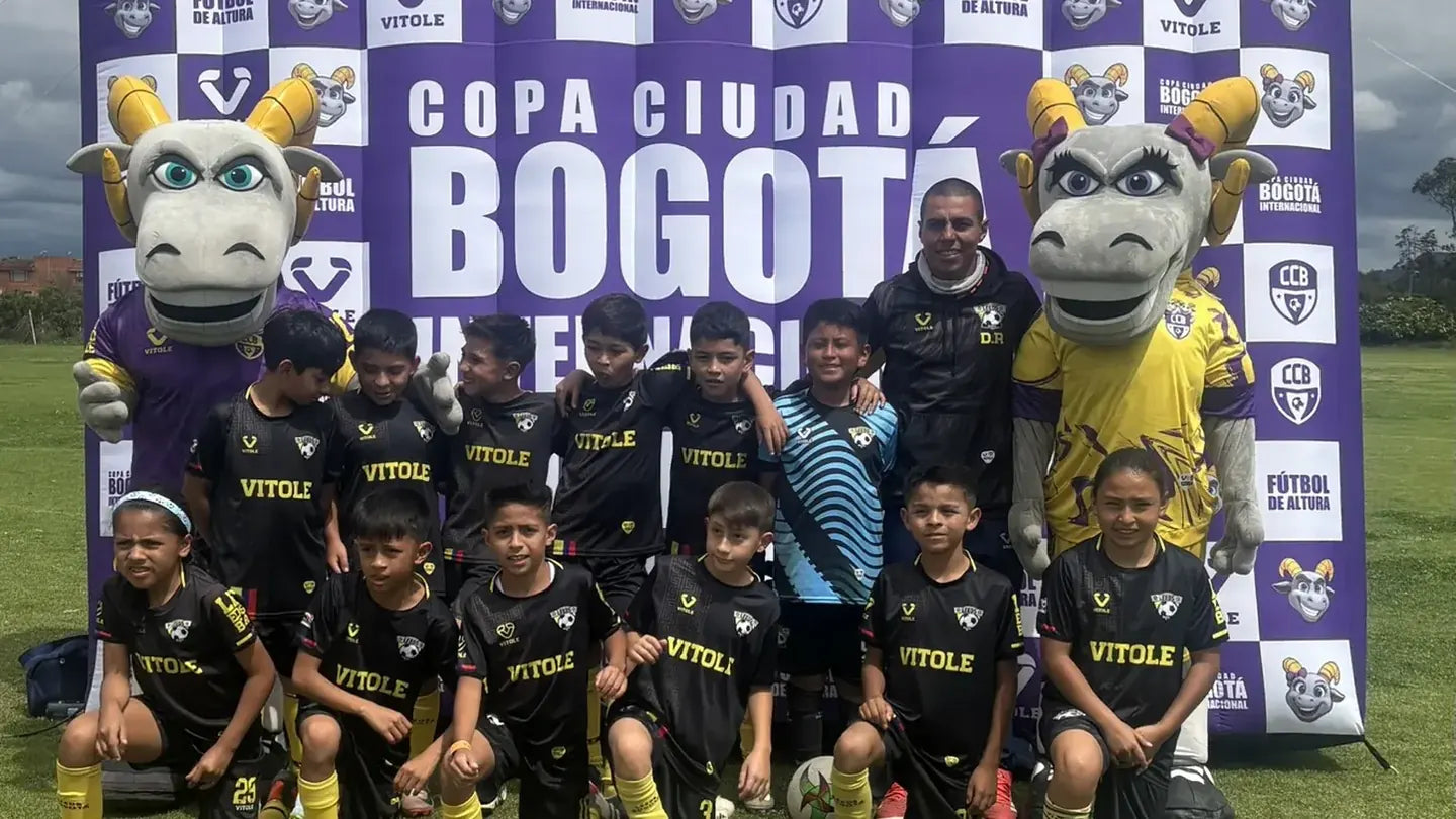 Equipo infantil frente al backdrop oficial de la Copa Ciudad Bogotá con las mascotas del torneo